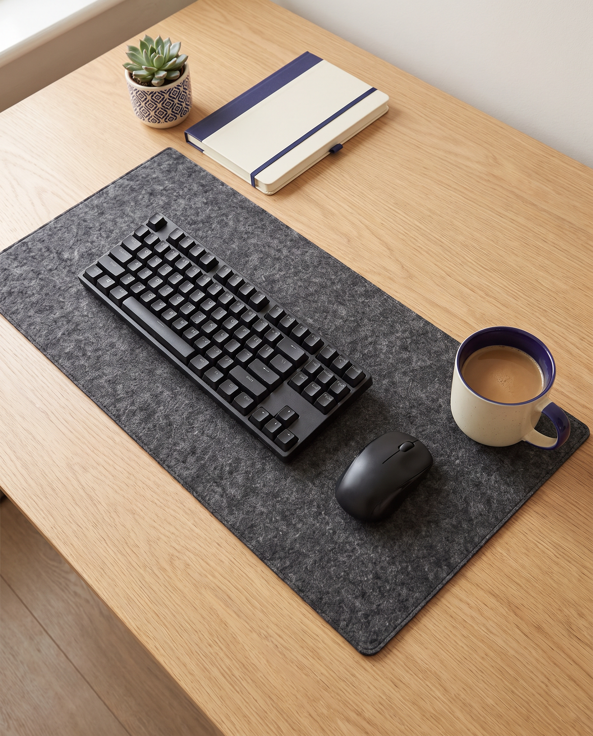 Setup de bureau vu de dessus avec sous-main en feutre, clavier et souris