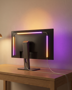 Bande LED RGBIC fixée au dos d'un écran, halo coloré sur le mur